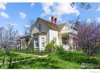Charming two-story home with a covered porch and balcony, surrounded by a lush green lawn and mature trees at 1341 N 95Th St, Lafayette, CO 80026