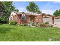 Charming brick home featuring a well-manicured lawn and vibrant flower beds enhancing its curb appeal at 1443 Elmhurst Ct, Longmont, CO 80503