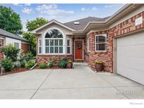 Charming single-story brick home with a well-maintained front yard and a red front door at 3413 Boxelder Dr, Longmont, CO 80503