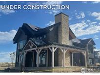 Craftsman-style home under construction featuring a stone chimney, dark siding, and a covered front porch at 917 Latigo Loop, Lafayette, CO 80026