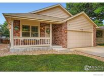 Charming brick home featuring a two-car garage, covered porch and landscaped front yard at 11156 W 64Th Pl, Arvada, CO 80004