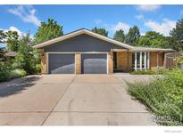 Charming single-story home with a brick facade, gray trim, two-car garage, and well-maintained landscaping at 1323 Horizon Ln, Longmont, CO 80501