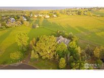 Expansive aerial view of a serene property with lush greenery and charming homes in the distance at 145 Brittany Ln, Lafayette, CO 80026