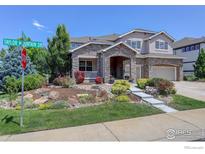 Charming two-story home featuring a stone facade and lush landscaping with a two car garage at 1504 Taylor Mountain Dr, Longmont, CO 80503