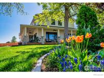 Inviting two-story home with a covered porch, lush lawn, and colorful flowers at 2017 Vaquero St, Longmont, CO 80504