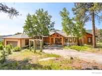 Charming single-story log cabin with stone accents, manicured trees, and a long private drive at 24043 Eagle Cliff Trl, Conifer, CO 80433