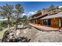 Stunning wood home featuring a stone chimney, viewing deck, and a large deck with expansive mountain views at 311 Sky Trail Rd, Boulder, CO 80302