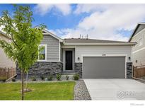 Charming home with gray siding, stone accents, manicured lawn, and a two-car garage at 4596 Hatcher Dr, Brighton, CO 80601