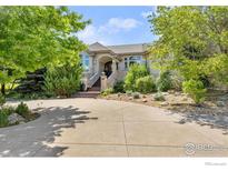 Stunning stone home with well-manicured landscaping and mature trees on a sunny day at 5288 Waterstone Dr, Boulder, CO 80301