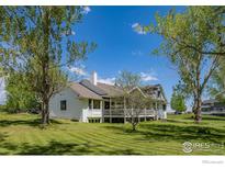 Expansive lawn and landscaping surround this bright home with white exterior and chimney at 5986 Heather Way, Longmont, CO 80503