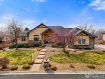 Charming home featuring stone accents, a gabled roof, manicured landscaping, and a beautiful walkway to the front door at 13866 W 76Th Pl, Arvada, CO 80005