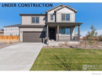 Inviting two-story home featuring a covered front porch, attached garage and well-manicured lawn at 1671 Pinnacle Ave, Lochbuie, CO 80601