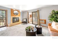 Cozy living room features a fireplace, a balcony, plush carpet, and ample natural light at 2800 Kalmia Ave # C205, Boulder, CO 80301