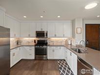 Modern kitchen featuring white cabinets, stainless steel appliances, and a stylish backsplash at 3301 Arapahoe Ave # 415, Boulder, CO 80303