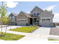 Charming home with a manicured lawn, stone accents, and attached two-car garage and lovely porch at 4918 Preserve Pl, Firestone, CO 80504