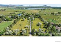 Expansive aerial view of the property with mature trees, landscaping, pond, and mountain views at 5575 Saint Vrain Rd, Longmont, CO 80503