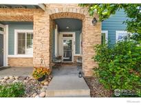 Charming home entrance features a stone archway and a well-manicured landscaped yard at 64 Whitehaven Cir, Highlands Ranch, CO 80129