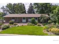 Charming brick home featuring a lush green lawn and mature trees at 7290 Mount Sherman Rd, Longmont, CO 80503