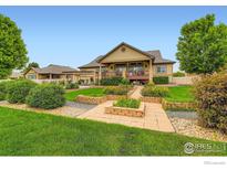 Beautiful backyard with a deck, a pergola, lush landscaping, and stone walkways at 9629 Bountiful St, Firestone, CO 80504