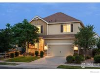 Inviting two-story home featuring a stone facade, covered porch, manicured lawn, and attached two-car garage at 1365 15Th Ave, Longmont, CO 80501