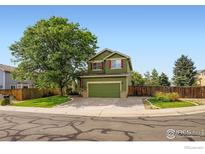 Charming two-story green home featuring a well-manicured lawn, mature trees, and inviting curb appeal at 1747 Daisy Ct, Brighton, CO 80601