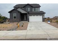Two-story gray home with stone accents, two-car garage, and landscaped front yard at 1759 Jennifer St, Brighton, CO 80601