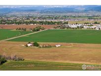 Expansive aerial view showcasing a home surrounded by lush green and brown fields, set against a mountain backdrop at 420 E County Road 10, Berthoud, CO 80513