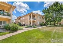 Inviting condo exterior with stone accents, well-maintained landscaping, and private balconies at 1703 Whitehall Dr # G, Longmont, CO 80504