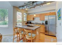Bright kitchen features a center island with seating, stainless steel appliances, and wood cabinets at 2850 E College Ave # 110, Boulder, CO 80303
