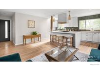 Bright living room featuring hardwood floors, an open layout, and a stylish kitchen island with barstool seating at 3089 S Jasmine St, Denver, CO 80222