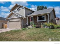 Charming two-story home featuring stone accents, a manicured lawn, and a welcoming front porch with an American flag at 6019 S Pierson Ct, Littleton, CO 80127
