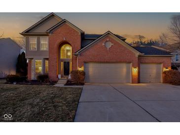 Brick two-story house with a three-car garage and well-manicured lawn at 12106 Cabri Ln, Fishers, IN 46037