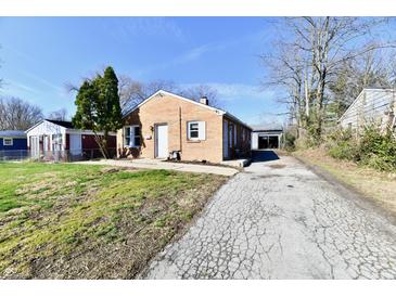 Cozy brick home featuring a spacious driveway leading to a detached garage in the backyard at 3612 Schofield Ave, Indianapolis, IN 46218