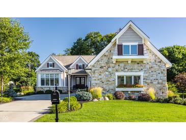 Charming stone-faced house with a well-manicured lawn and beautiful landscaping at 340 Beechwood Farm Ln, Indianapolis, IN 46260