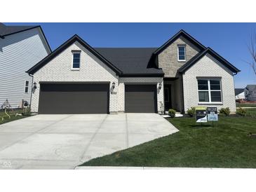 Charming two-story home boasts a white brick facade, stone accents, a dark roof, and a two-car garage at 4982 Reavie Ct, Noblesville, IN 46062