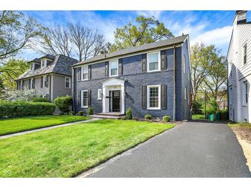 Charming two-story home with a brick facade, black shutters, manicured lawn, and inviting walkway at 22 W 54Th St, Indianapolis, IN 46208