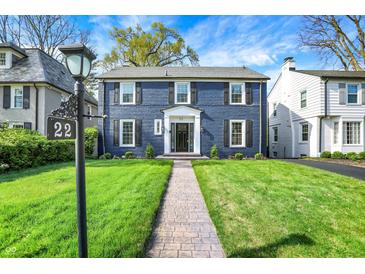 Charming two-story home with a brick facade, black shutters, manicured lawn, and inviting walkway at 22 W 54Th St, Indianapolis, IN 46208