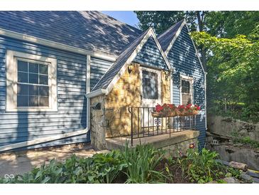 Charming blue home showcasing a stone accent, flower boxes on the porch and a landscaped garden at 327 Central Ave, Anderson, IN 46012
