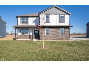 Two-story home showcasing a brick and vinyl exterior, complemented by a well-maintained lawn under a clear blue sky at 7888 Magnolia St, New Palestine, IN 46163