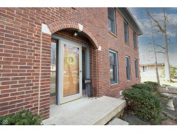 Charming brick home featuring an arched entryway and a well-maintained lawn at 10909 Wonderland Dr, Indianapolis, IN 46239