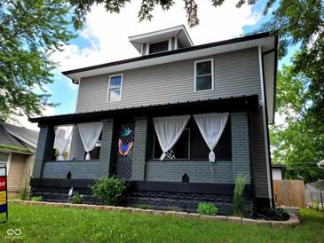 Charming two-story home featuring gray siding, a covered porch with white curtains and a colorful butterfly decoration at 2828 Robson St, Indianapolis, IN 46201