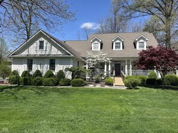 Charming home featuring a meticulously landscaped front yard, quaint wooden walkway, and beautiful trees in a suburban setting at 1612 S Jeanne Ct, New Palestine, IN 46163