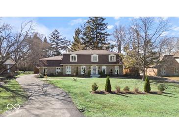 Charming stone-clad home featuring a well-manicured lawn and an asphalt driveway at 6906 Johnson Rd, Indianapolis, IN 46220