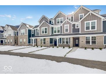 New townhome community with modern gray and brick exteriors, snow-covered landscaping, and attached garages at 5759 Cr W 750 N, McCordsville, IN 46055