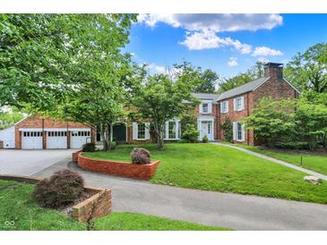 Charming brick home with lush landscaping, mature trees, and a spacious driveway leading to the garage at 2505 Riverside Dr, Columbus, IN 47201