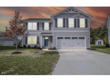 Charming two-story home with a manicured lawn, two-car garage, and blue front door at 975 Red Hills Ct, Lebanon, IN 46052