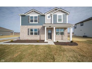Charming two-story home with brick and siding facade, covered front porch, and well-maintained lawn at 7904 Magnolia St, New Palestine, IN 46163