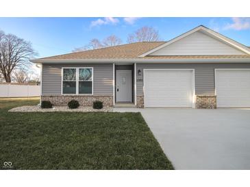Gray siding two-car garage home with a landscaped lawn and white fence at 1501 Coen Ct, Columbus, IN 47201