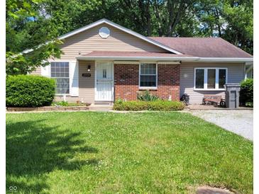 Tan house with brick accents, green lawn, and a partially visible driveway at 3359 Laurel St, Indianapolis, IN 46227