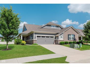 Charming home featuring a well-manicured lawn, gray siding, brick accents, and attached two-car garage at 17345 Northam Dr, Westfield, IN 46074